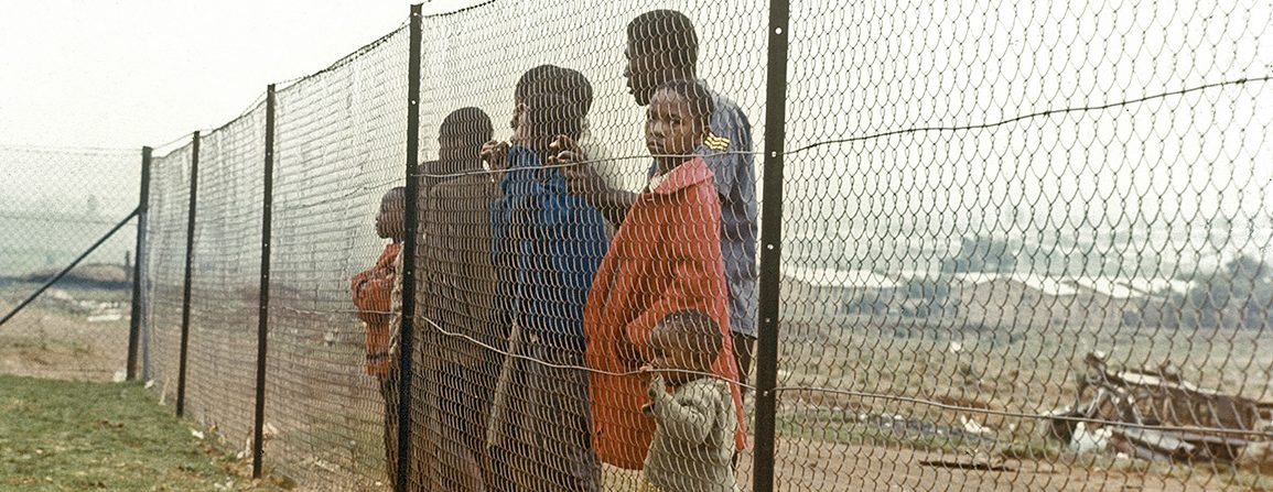 Children behind fence that separates them from the white community near Johannesburg during time of apartheid in South Africa.